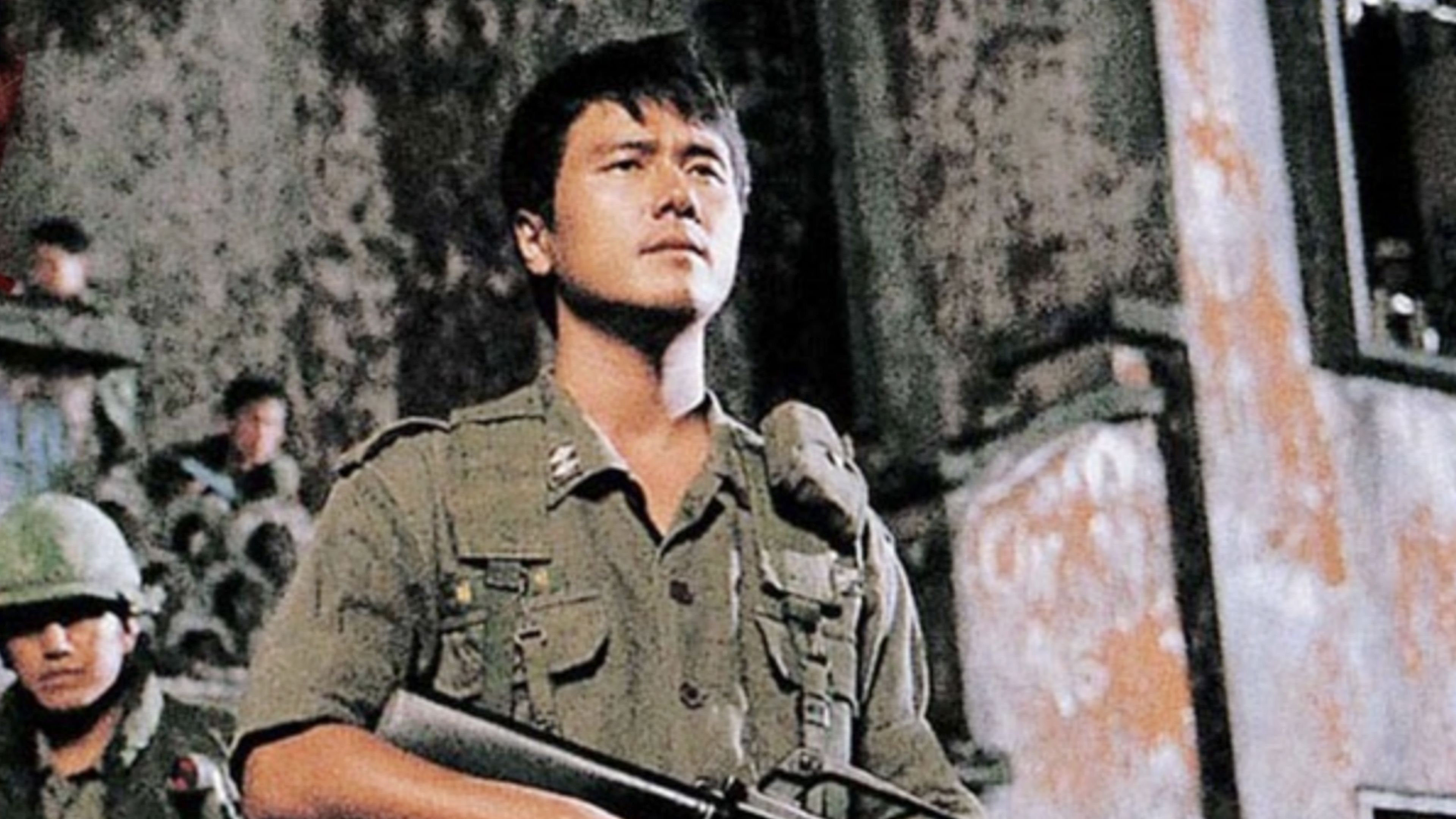 A South Korean soldier carrying a rifle stands with other troops at an abandoned compound in the Vietnam War horror movie R-Point.