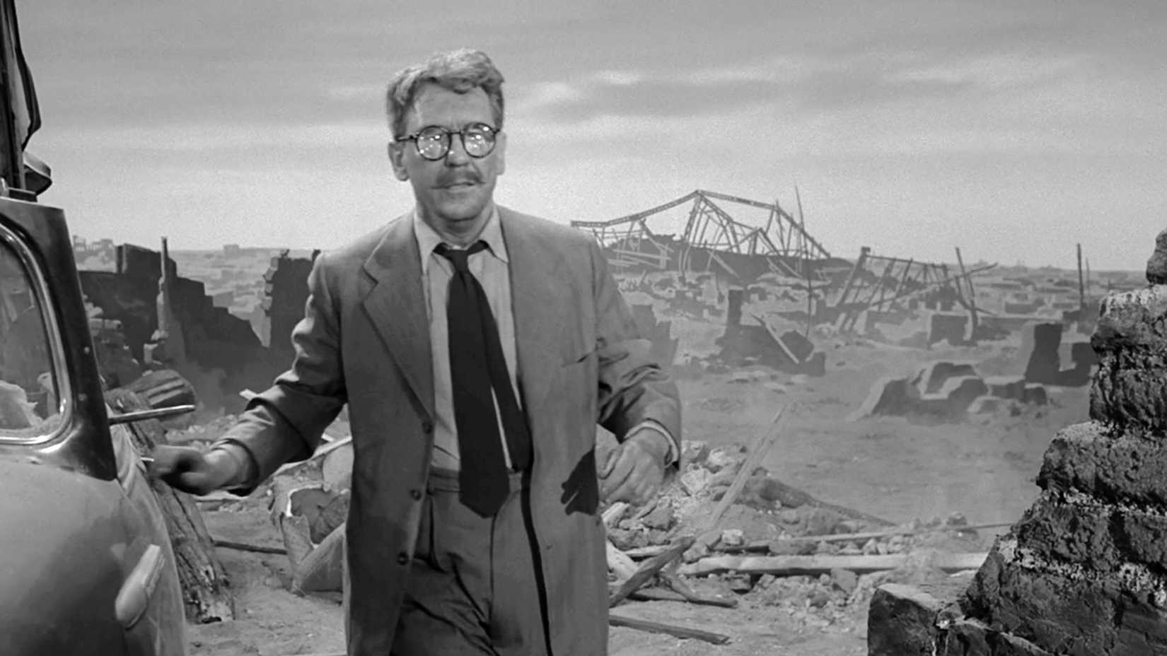 A bespectacled man stands amid the ruins of a destroyed city in The Twilight Zone episode “Time Enough at Last.”